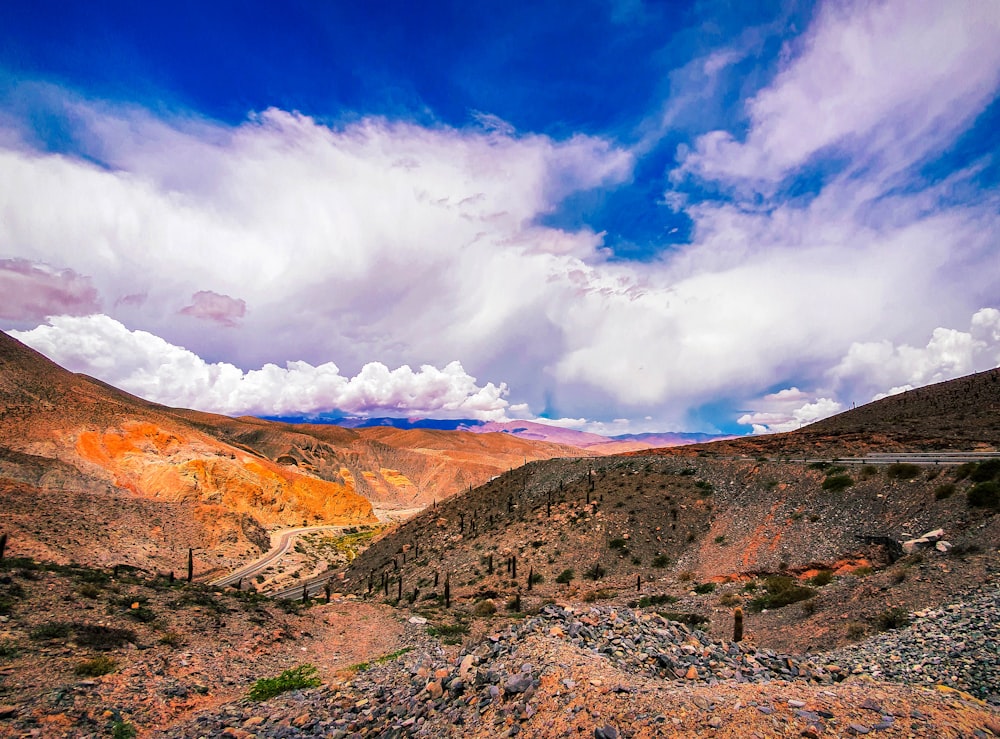 brown and green mountains under white clouds and blue sky during daytime