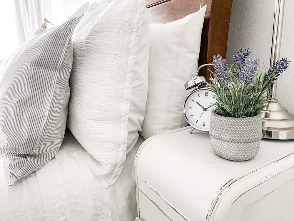 white and silver analog alarm clock on white couch