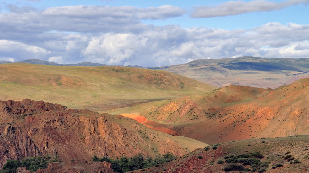 brown and green mountains under white clouds during daytime