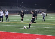 A player skillfully dribbling past defenders under bright stadium lights.