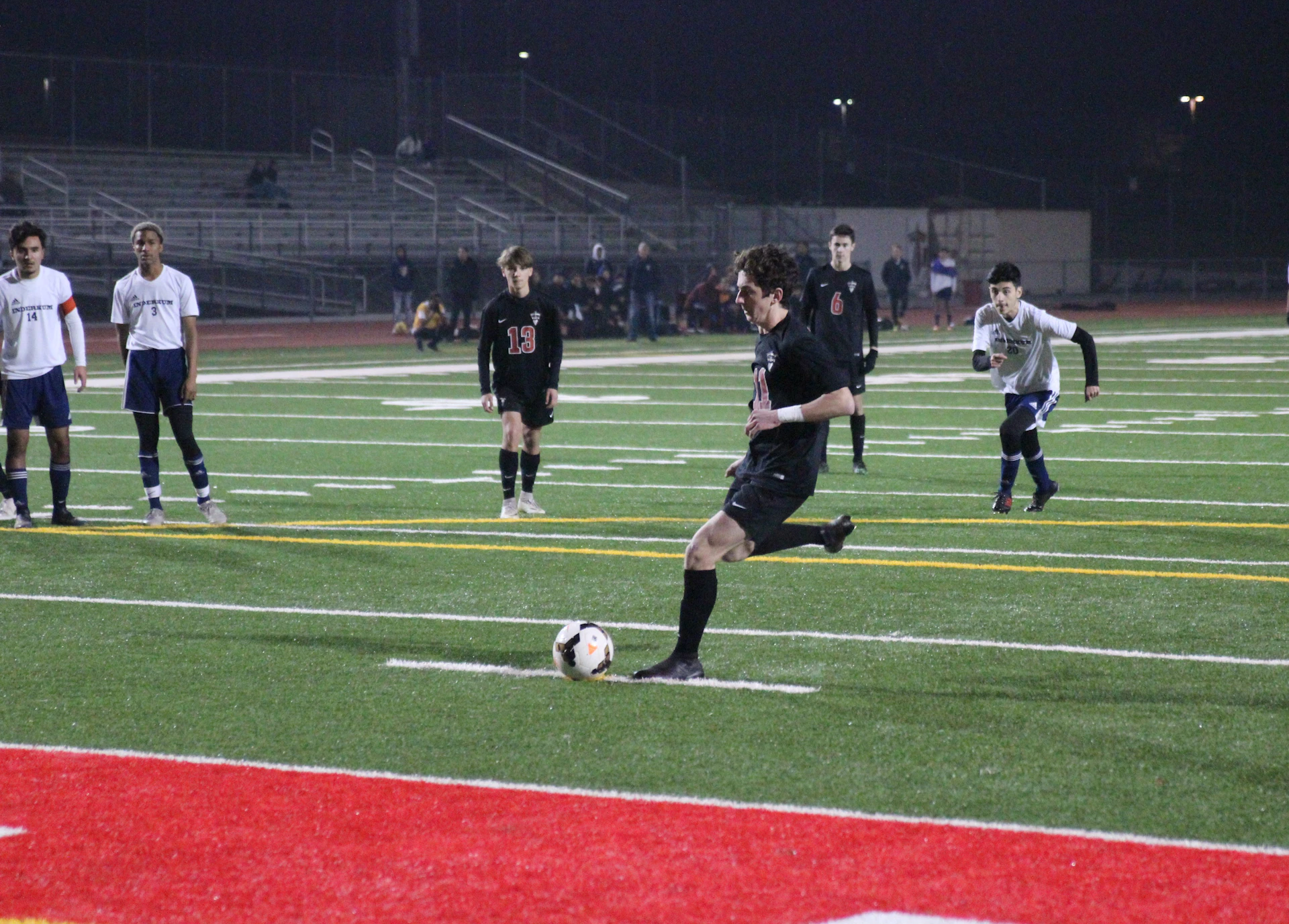 Action shot of a soccer player mid-kick on a vibrant green field under stadium lights