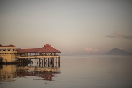 brown wooden house on body of water during daytime in Manado Indonesia
