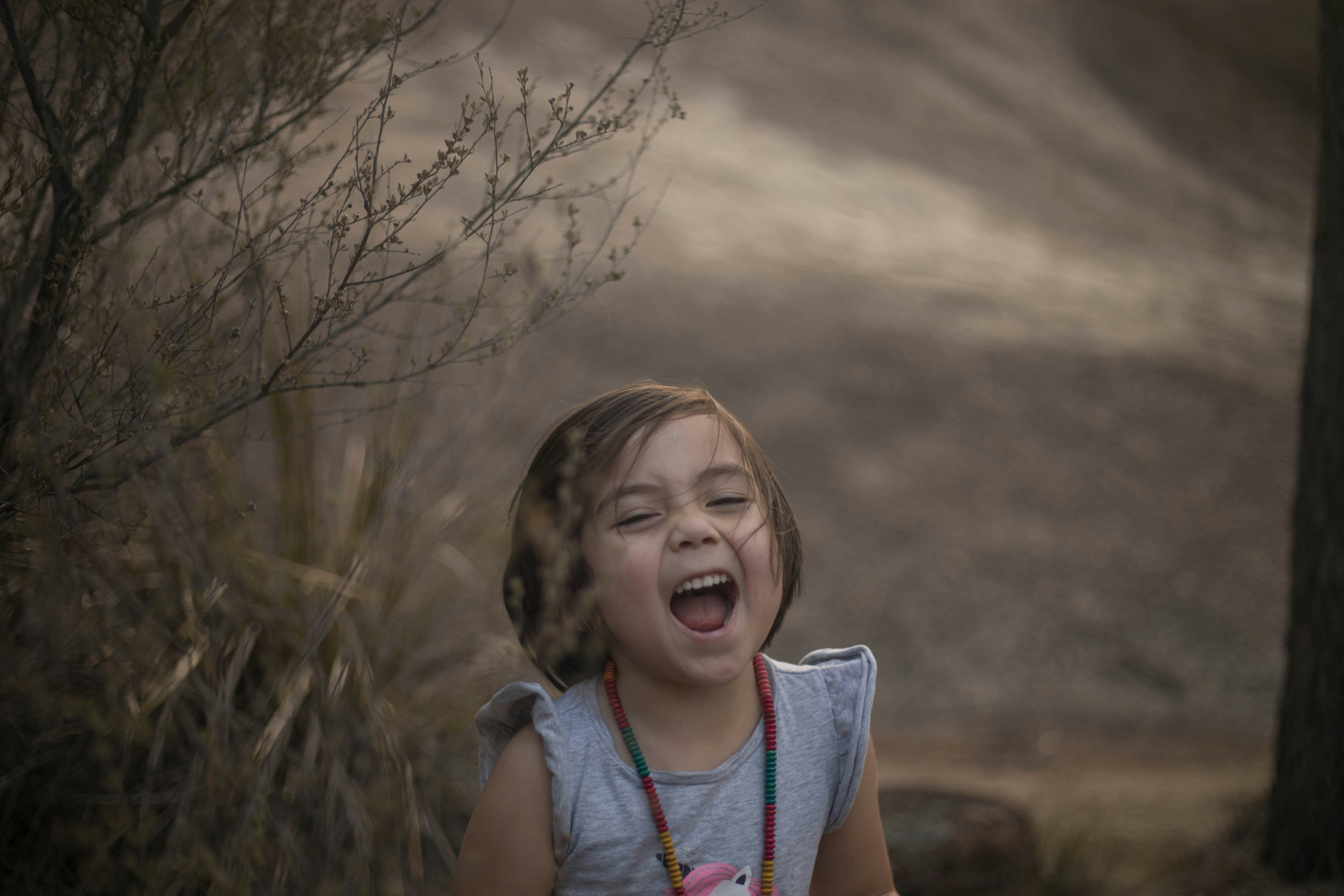 girl in blue and red tank top standing on brown grass field during daytime