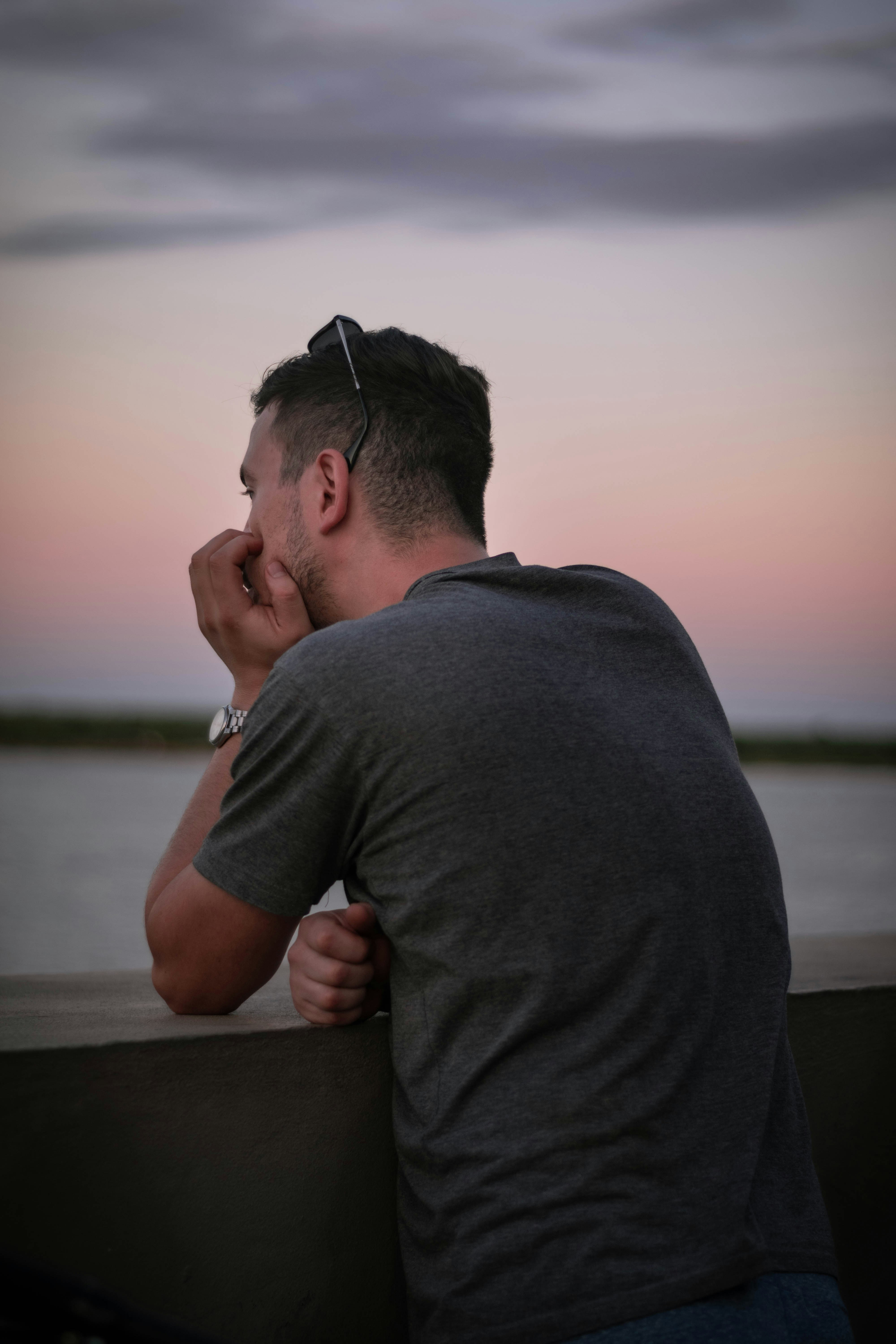 man in gray crew neck t-shirt sitting on brown wooden bench during daytime