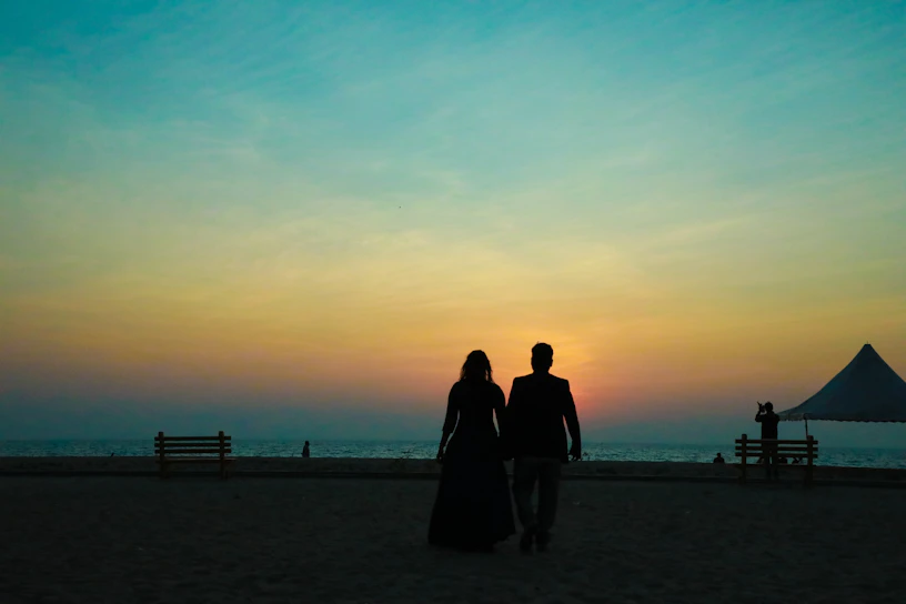 A romantic Latino couple enjoying a sunset walk on a Caribbean beach, hand in hand.