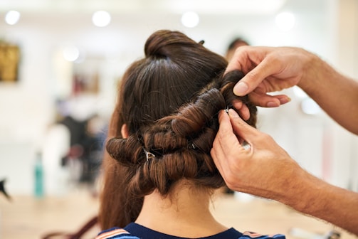 A hairstylist working on an elegant updo for a bride.