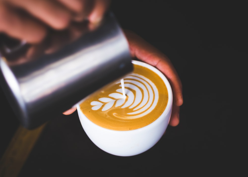 person holding white ceramic mug with brown liquid