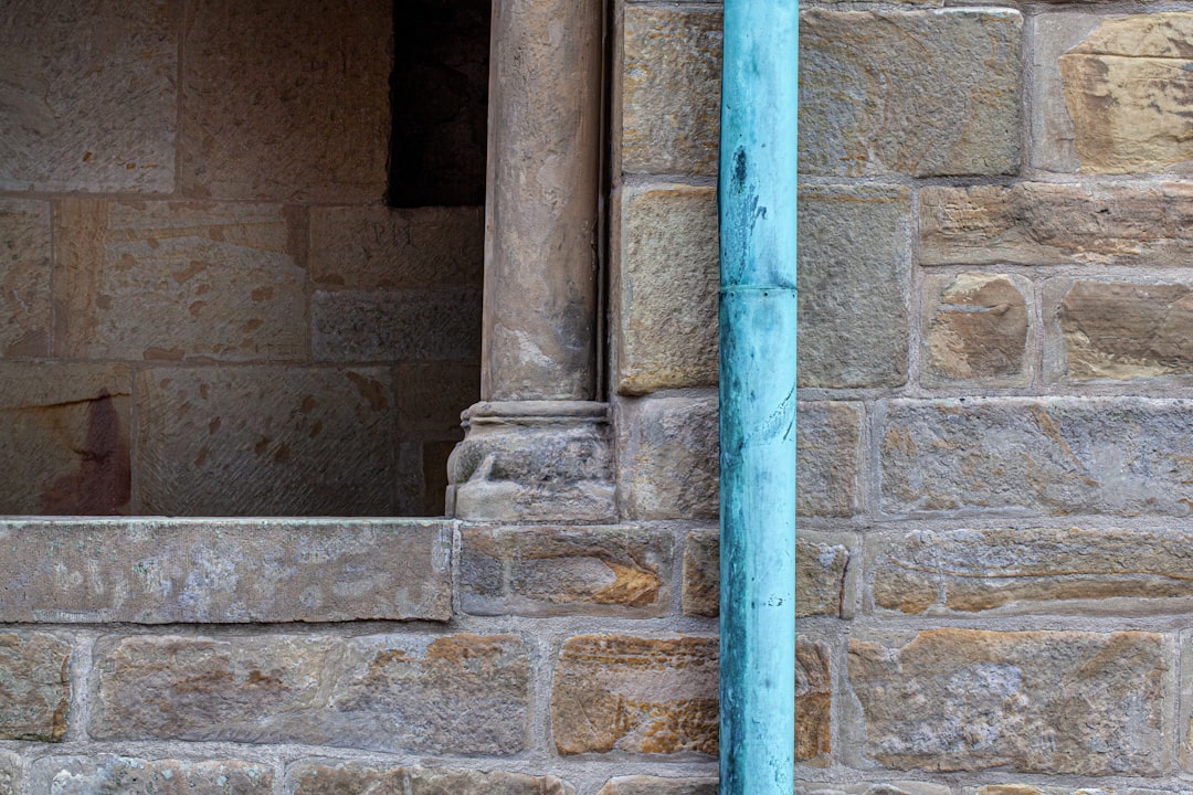 blue metal pipe on brown concrete wall