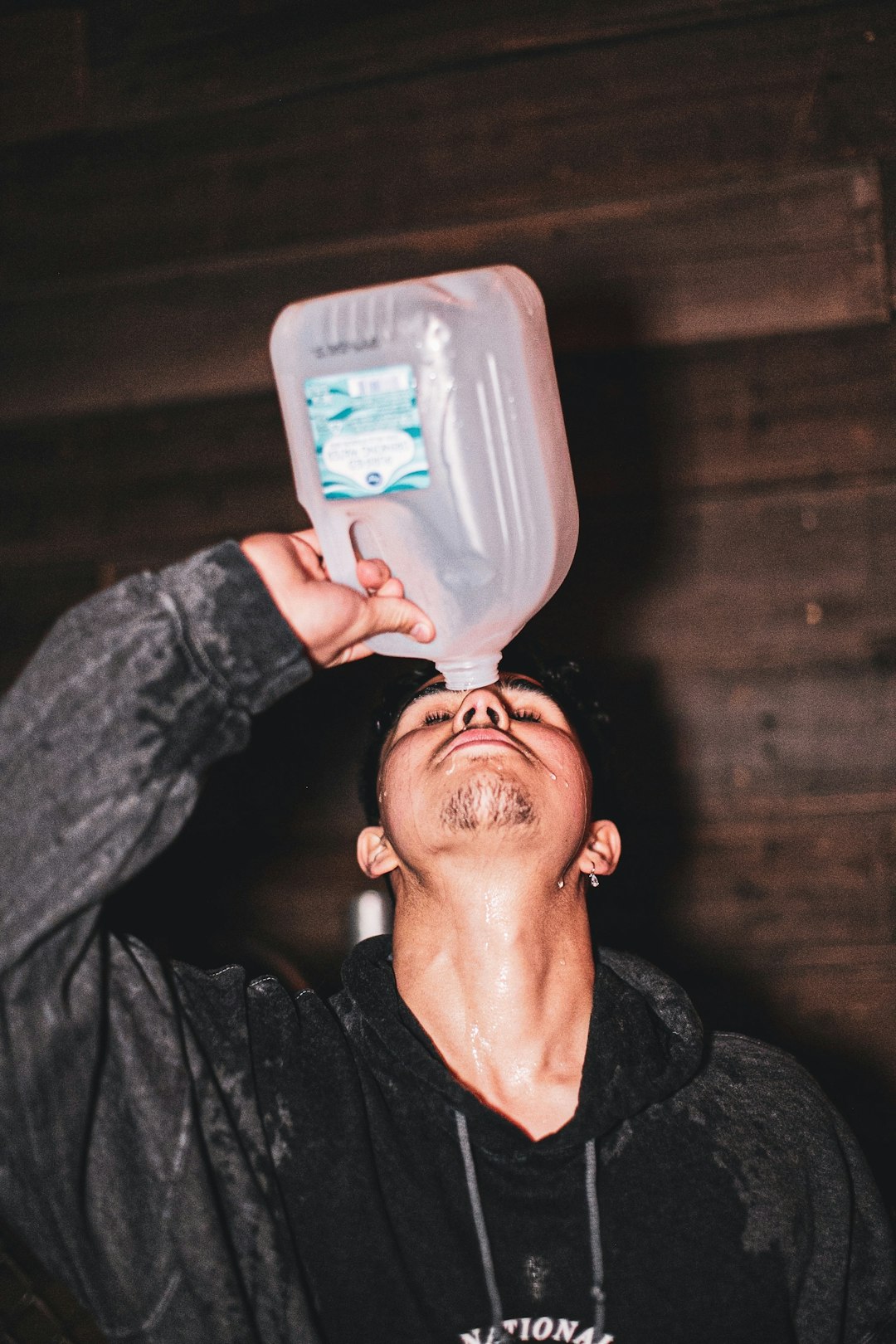 man in black jacket holding blue plastic container