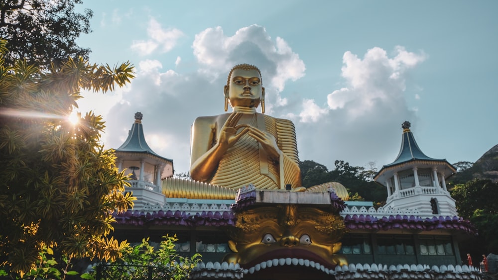 estátua de ouro de buddha sob o céu nublado durante o dia