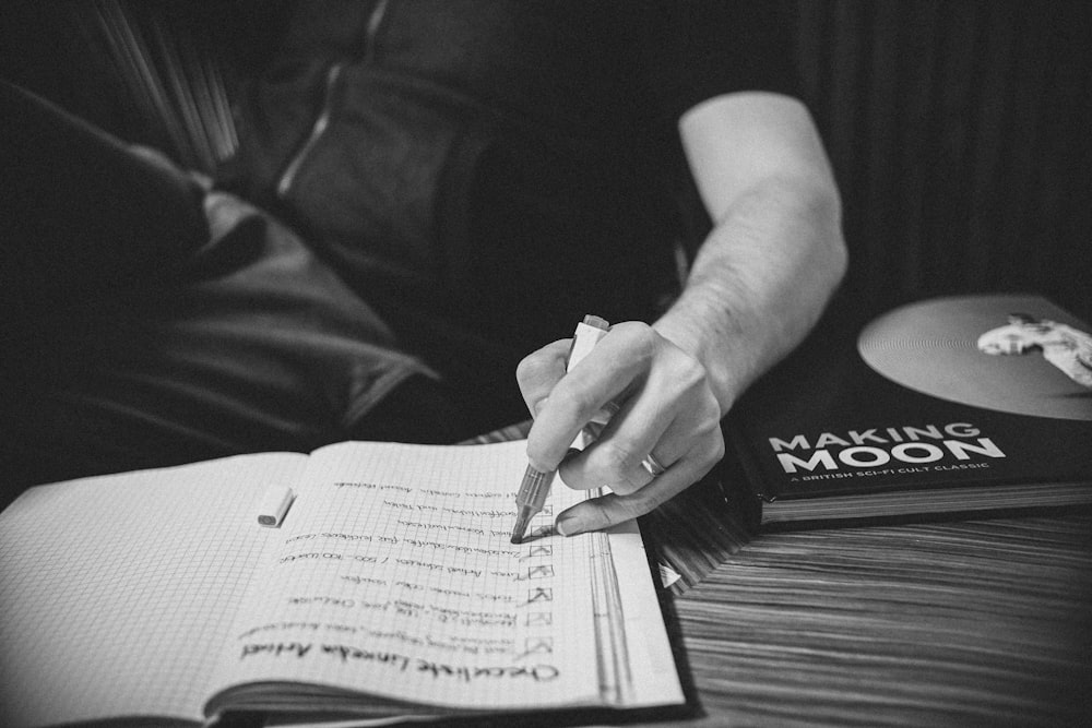 grayscale photo of person writing on paper