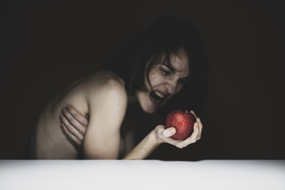 topless woman holding red apple