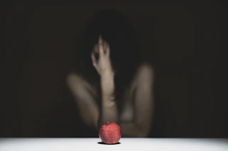woman covering her face with red apple