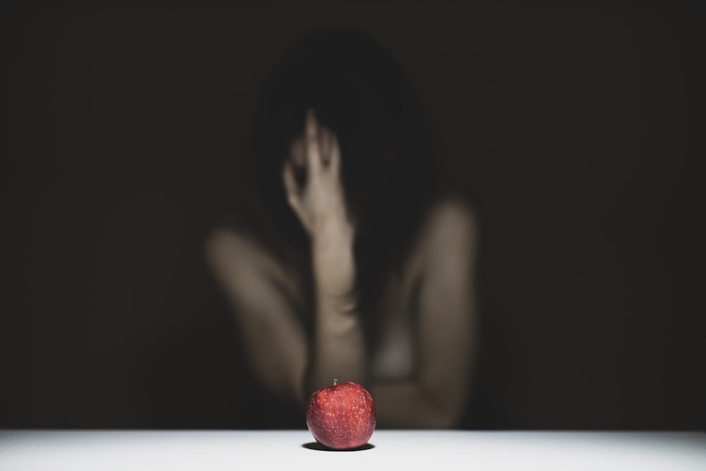 femme se couvrant le visage avec de la pomme rouge