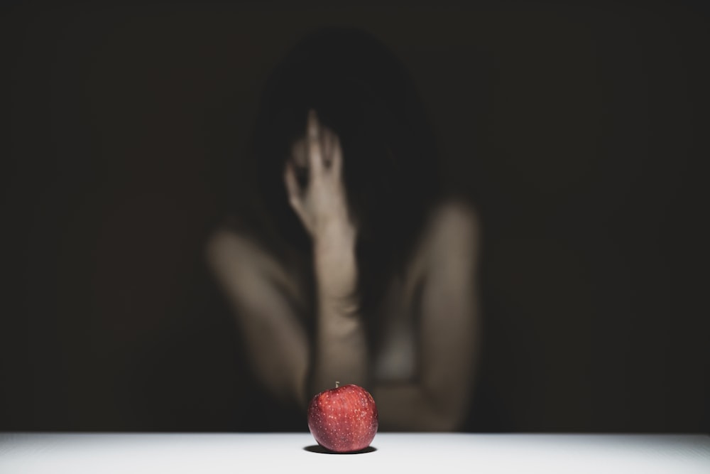 mujer cubriéndose la cara con manzana roja