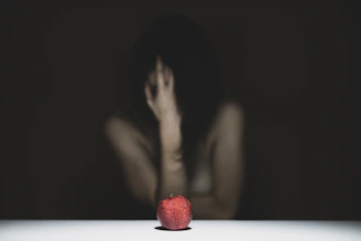woman covering her face with red apple