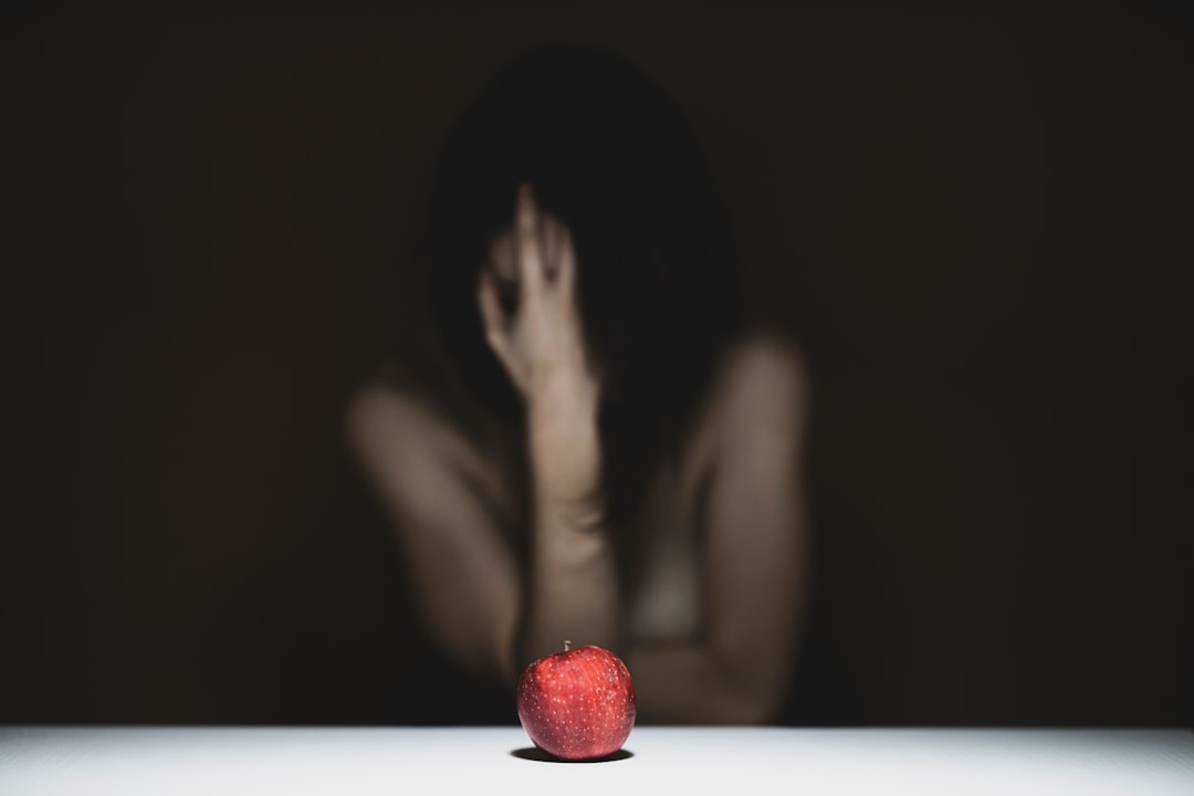 woman covering her face with red apple