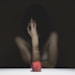 woman covering her face with red apple