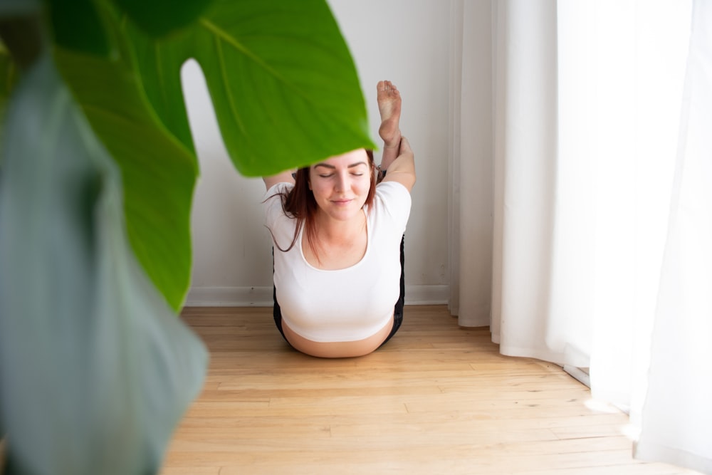 woman in white tank top and white panty standing on brown wooden parquet floor