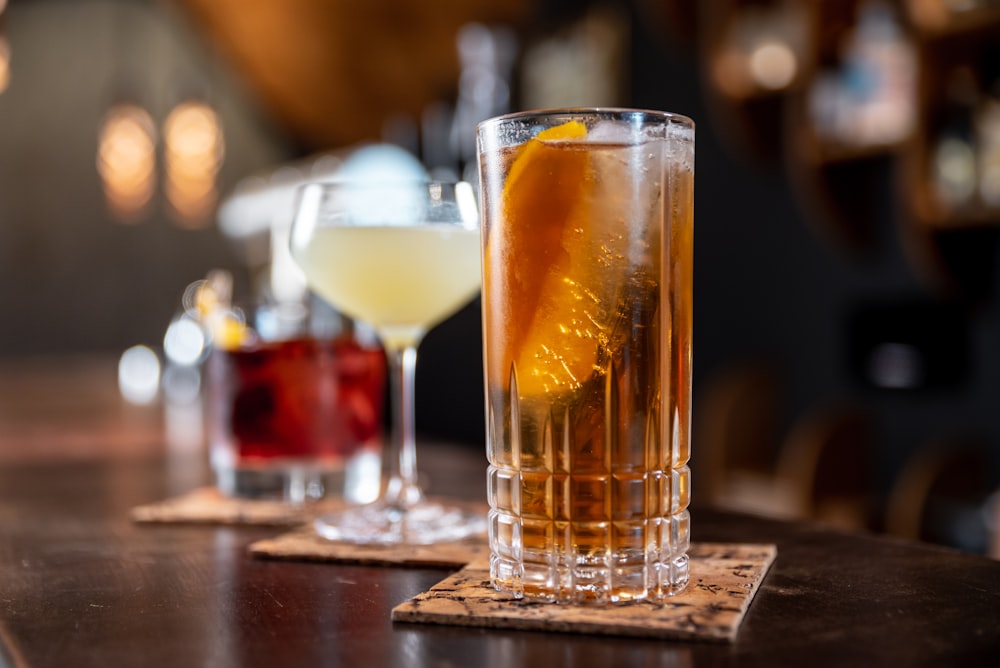 clear drinking glass with orange liquid on brown wooden table