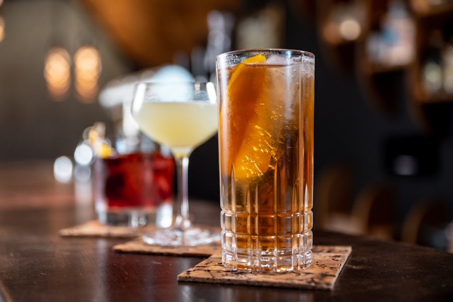 Tall whisky glass with iced amber spirit on dark wood bar