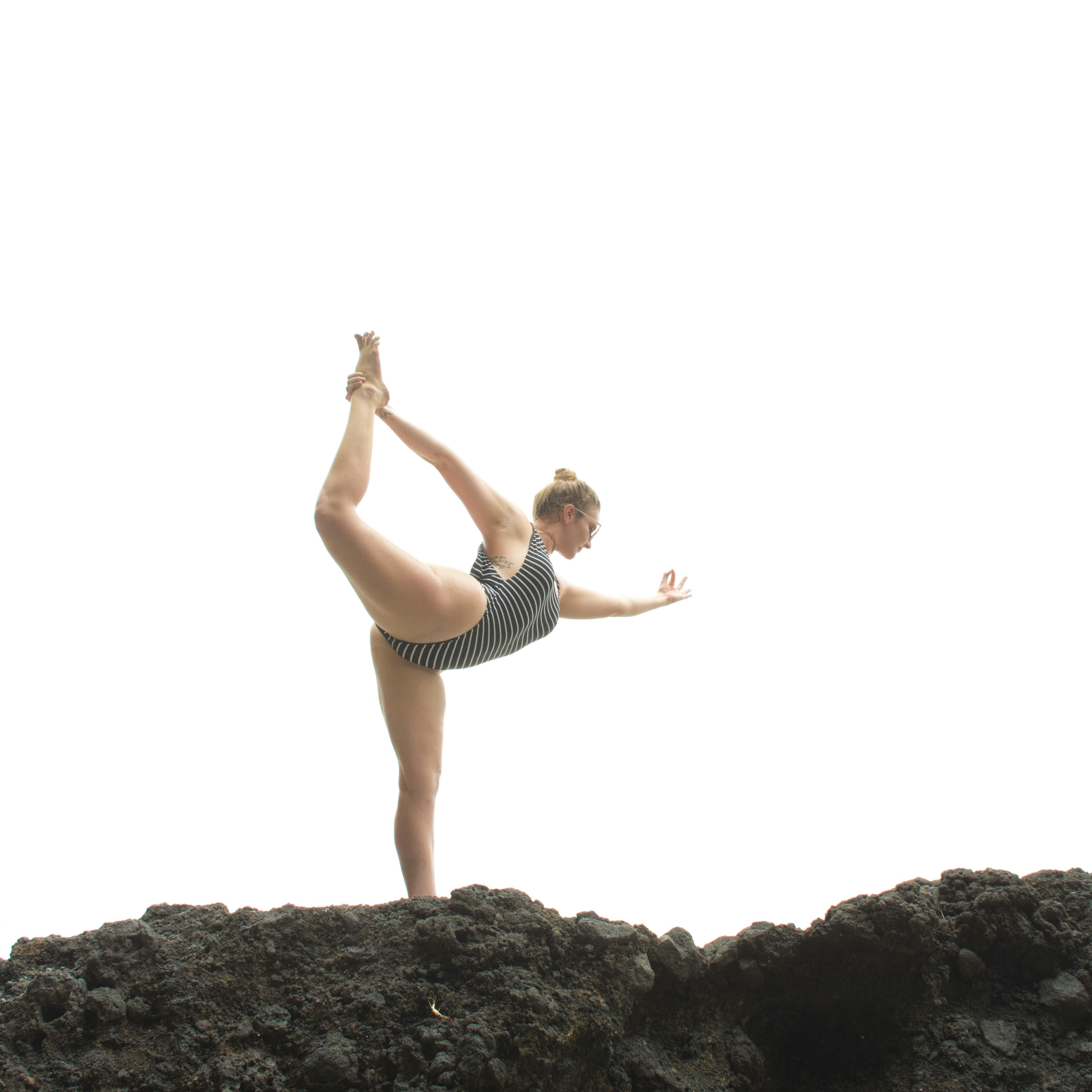 woman in black tank top and black shorts standing on rock during daytime