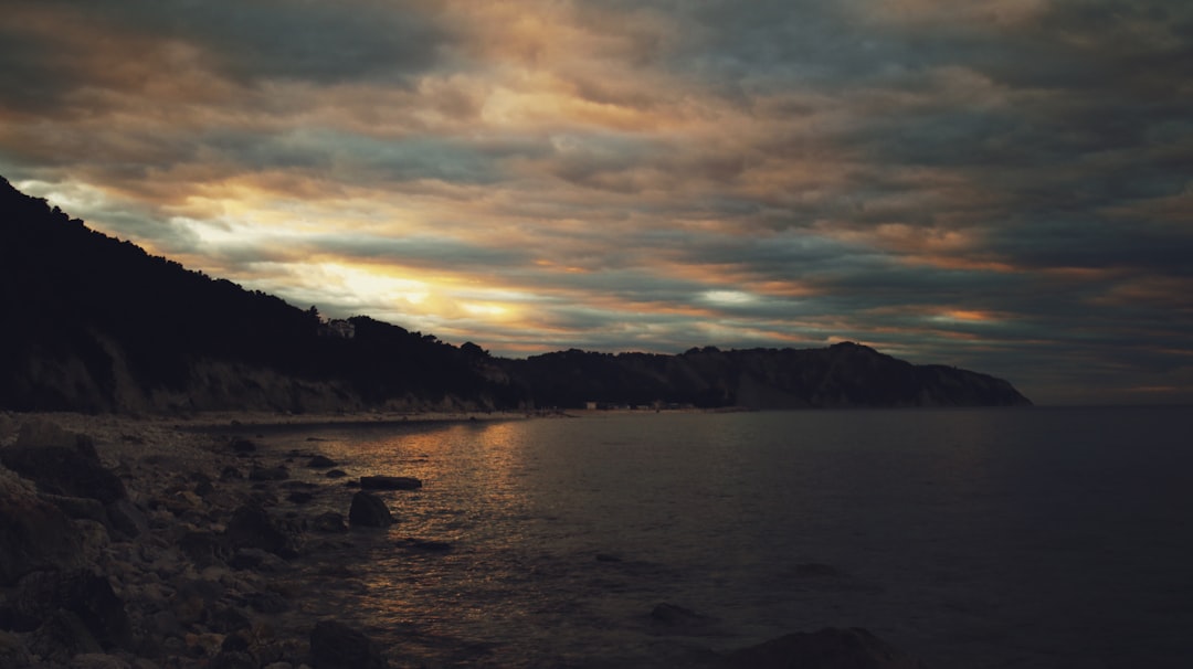 body of water near mountain during sunset