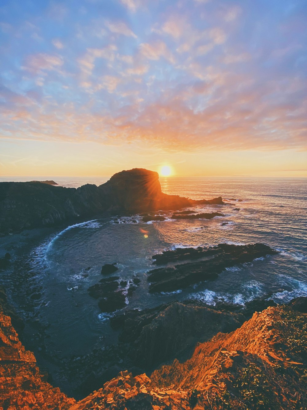 Formation rocheuse brune sur la mer au coucher du soleil