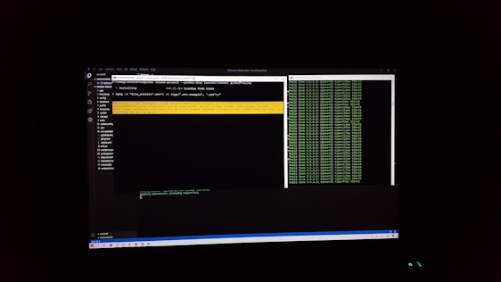 The image features a computer screen displaying a coding environment. The screen shows a text editor with various files and folders listed on the left-hand side, while the main coding area is open with a command line interface. There are green text outputs typical of command line operations performed on a black background.
