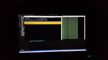 The image features a computer screen displaying a coding environment. The screen shows a text editor with various files and folders listed on the left-hand side, while the main coding area is open with a command line interface. There are green text outputs typical of command line operations performed on a black background.