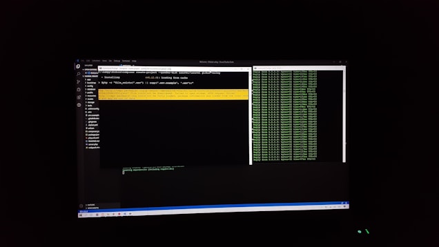 The image features a computer screen displaying a coding environment. The screen shows a text editor with various files and folders listed on the left-hand side, while the main coding area is open with a command line interface. There are green text outputs typical of command line operations performed on a black background.
