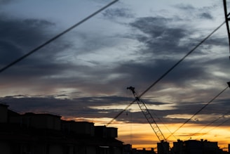 A dramatic sunset over a city skyline, with silhouettes of buildings and cranes.