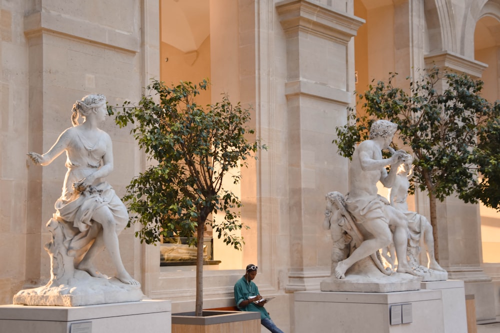 man in black jacket sitting beside statue of man