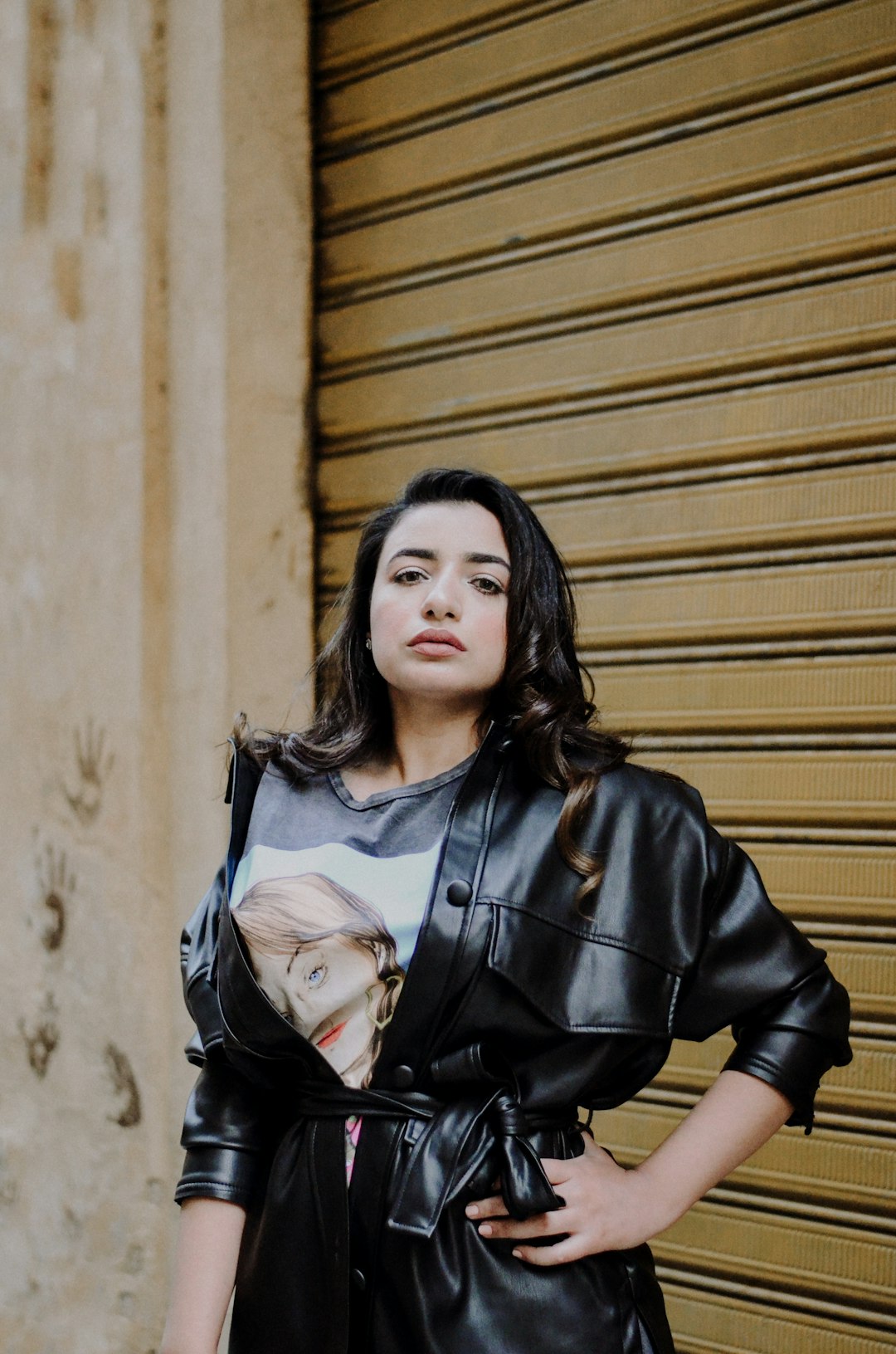 woman in black leather jacket standing beside brown wall