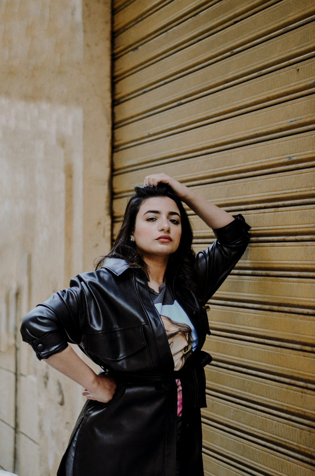 woman in black leather jacket standing beside brown wooden wall