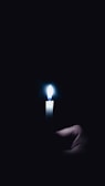 Hands gently holding a glowing candle in a dimly lit room.