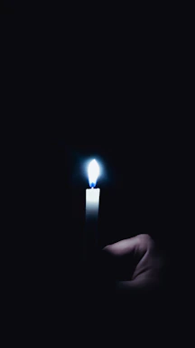 A gentle hand holding a paw print-shaped candle glowing softly in the dark