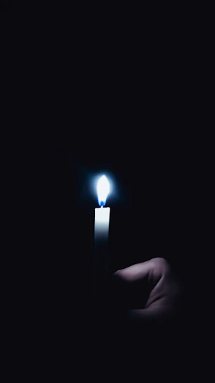 Hands gently holding a glowing candle in a quiet chapel, symbolizing hope and prayer.