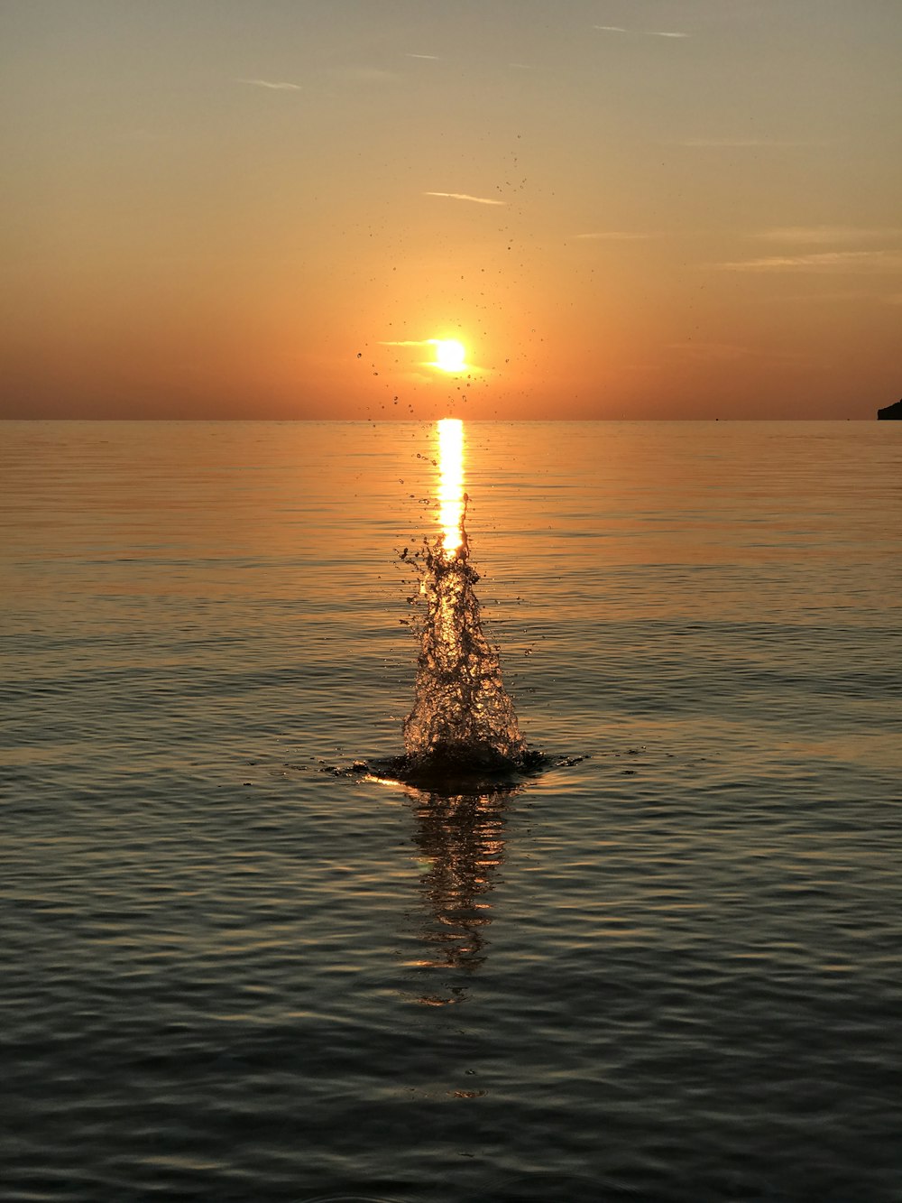 silhouette of person on body of water during sunset