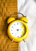 Yellow clock on a blanket, representing a consistent morning and evening skincare routine