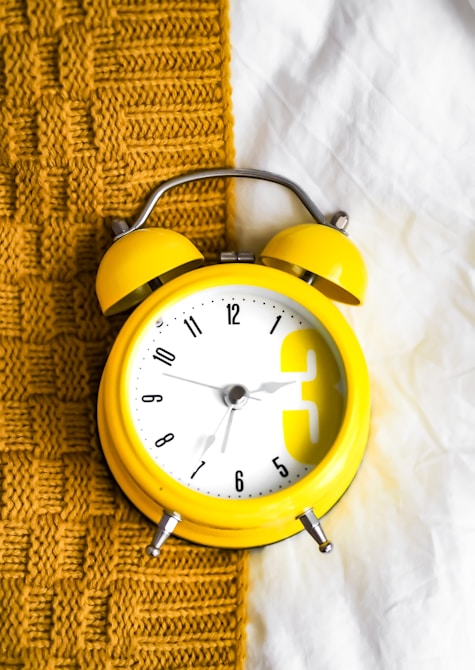 Yellow clock on a blanket, representing a consistent morning and evening skincare routine