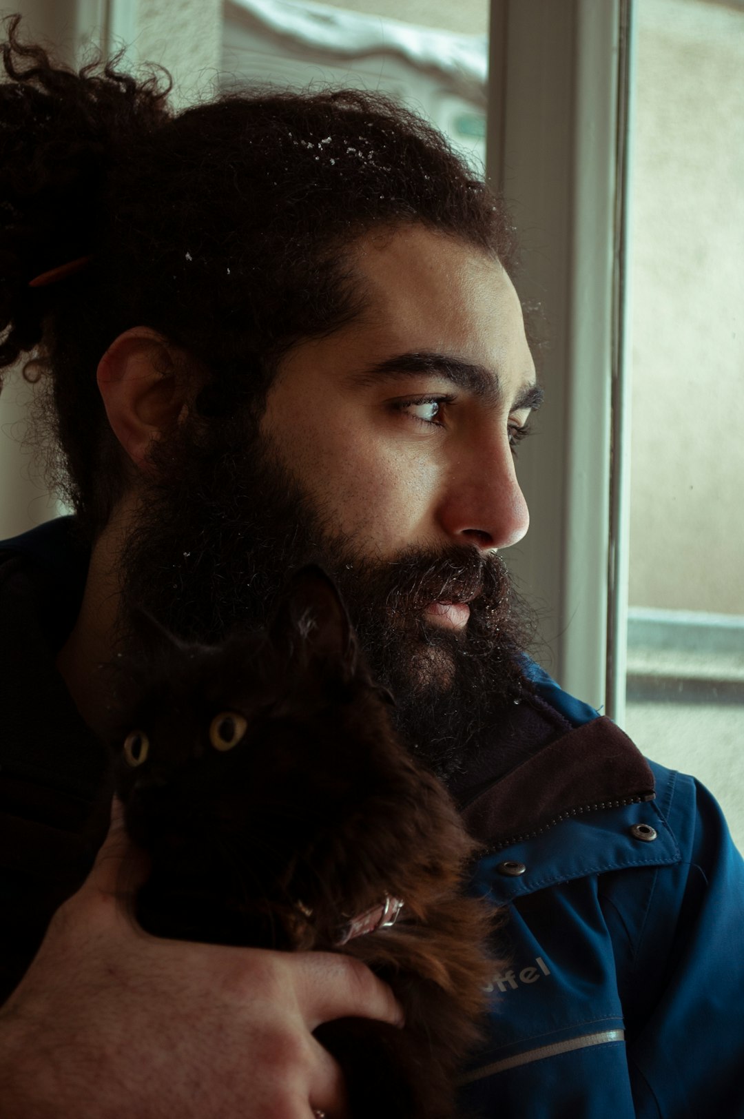 man in blue denim jacket beside black cat