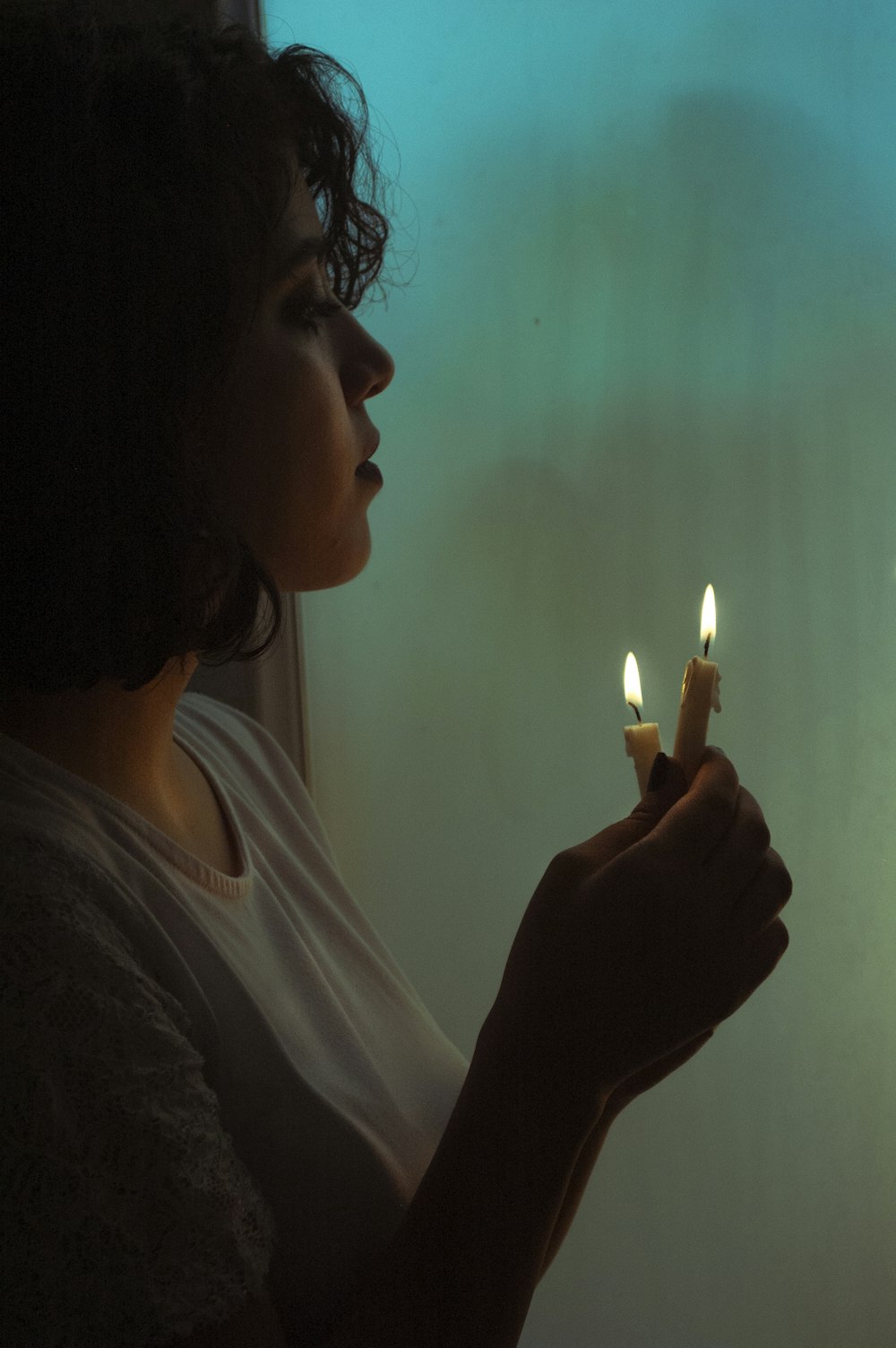woman in white shirt holding lighted candle