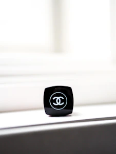 A close-up shot of a sleek, stylish makeup bag with soft pastel tones, placed on a clean white surface with subtle shadows.