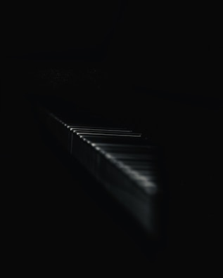 Softly blurred image of a piano keyboard under dim, atmospheric lighting.