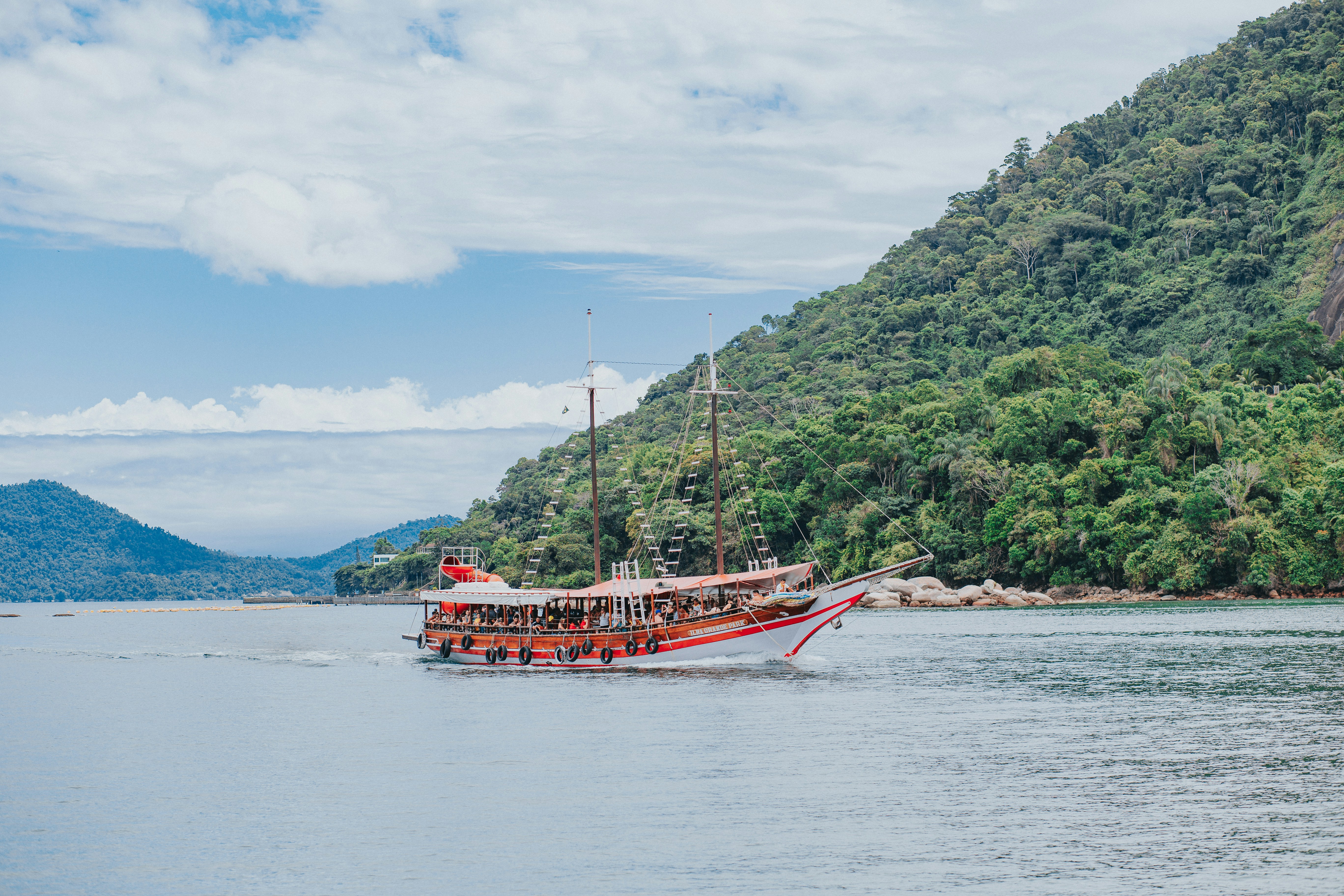 red boat on sea near green trees under white clouds and blue sky during daytime feliz navidad zoom background