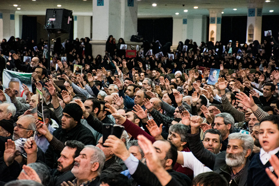 Crowd of people raises hands in unison, men and women face center together