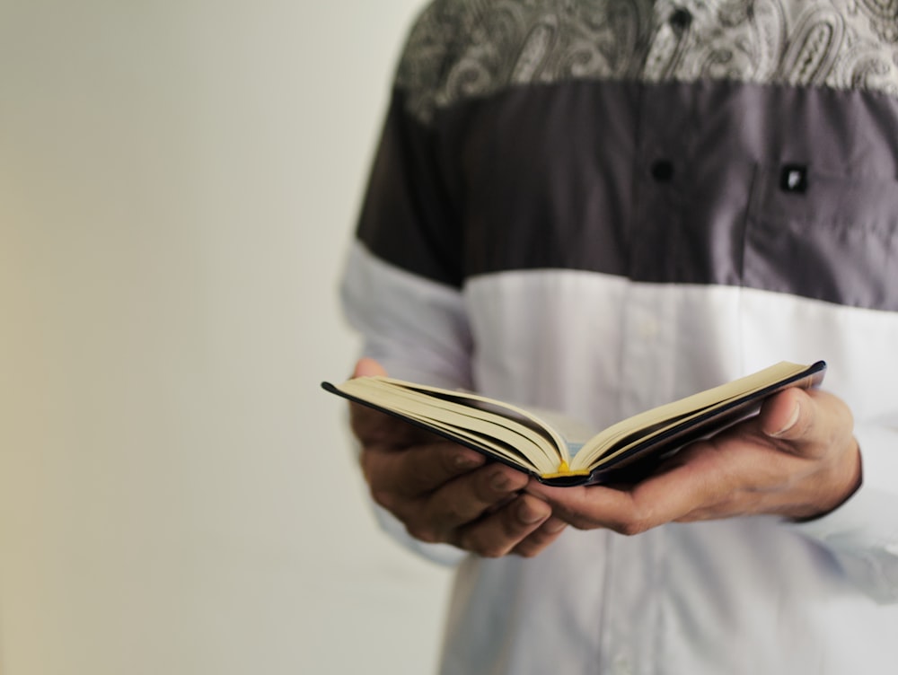 person in black and gray button up shirt reading book