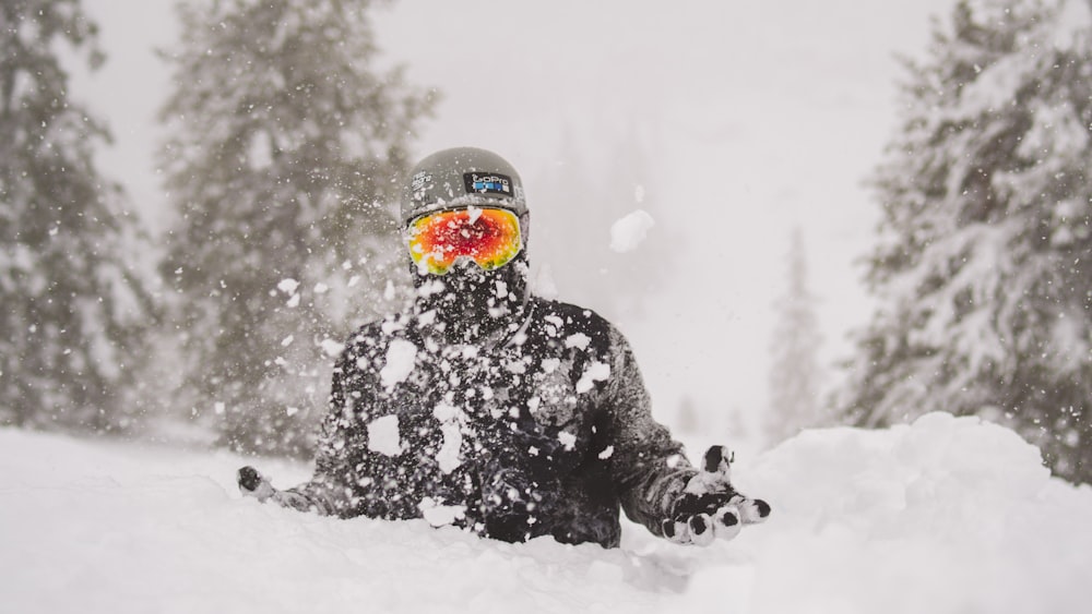 Persona con chaqueta negra y casco naranja en suelo cubierto de nieve durante el día