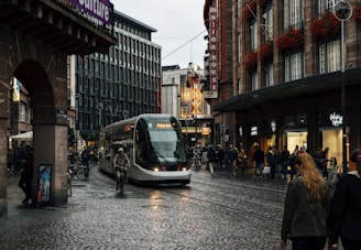 people walking on sidewalk near white and black tram during night time
